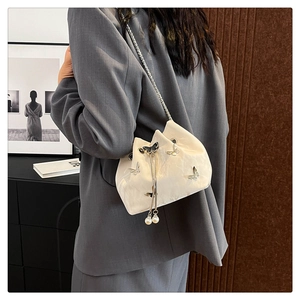 Detail of cream drawstring bucket bag with butterfly accents and pearl drawstring charms