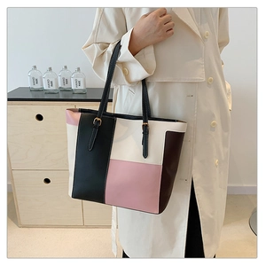 Detail of color-block tote bag with adjustable golden buckles and contrast stitching