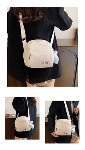 Detail of off-white nylon shell bag with purple Luck You patch and blue plush charm