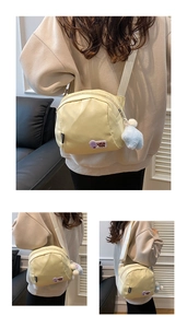 Detail shots of cream yellow nylon shell bag with purple text patch and blue pompom