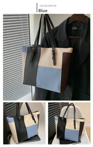 Detail of color-block tote bag with blue and black panels and adjustable gold buckle