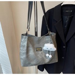 Détail du sac cabas gris avec patch MiaTmait et accessoire en peluche nuage blanc