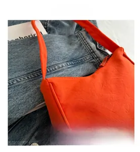 Detail view of the bright orange nylon shoulder bag featuring a smooth zip closure