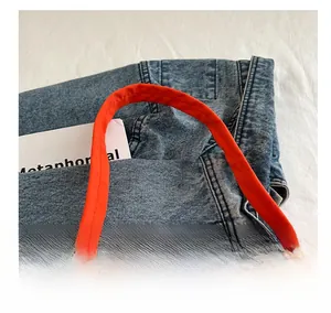 Close-up of bright orange nylon crescent bag handle and metal zipper detail