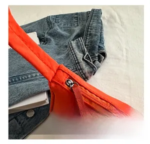 Detail shot of smooth zipper closure on vibrant orange nylon underarm bag for women