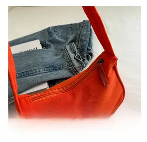 Detail view of the orange canvas hobo bag with matching strap and smooth dark metal zipper