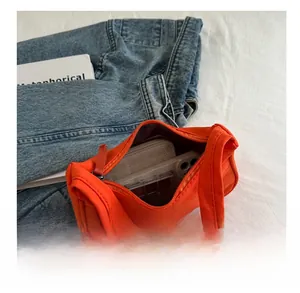 Spacious interior of a bright orange crescent bag holding a phone, wallet and makeup palette