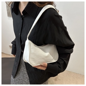 Side view of white crescent shoulder bag with soft textured faux leather finish