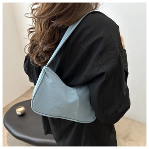 Detail of light blue crescent shoulder bag featuring smooth nylon texture on a model