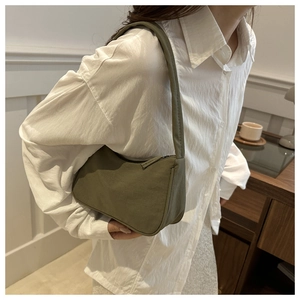 Olive green crescent shoulder bag in matte nylon shown worn by a model for size and scale