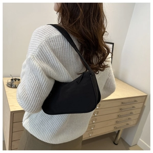 Detail of minimalist black nylon hobo bag on model showing sleek crescent shape and strap