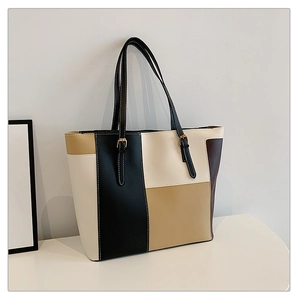 Detail of color-block tote bag showing adjustable shoulder strap and gold metal buckle