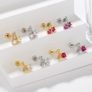 Detailed view of screw-back cherry and bow earrings with zircon stones in gold and silver