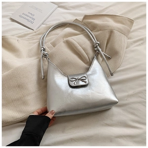 Detail of silver metallic hobo bag featuring a decorative metal bow and knotted strap