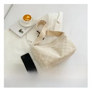 Cream woven dumpling bag shown next to a smartphone to demonstrate large storage capacity