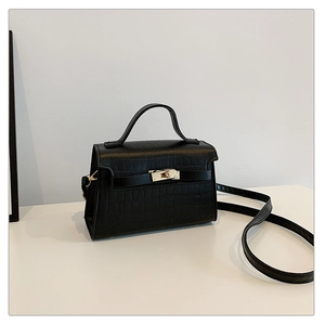 Detail of black crocodile texture leather bag with elegant golden twist lock and top handle