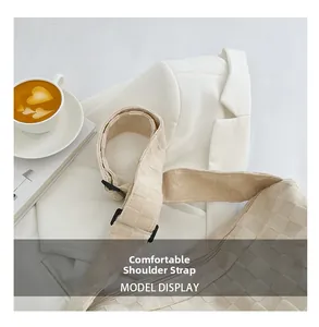 Détail de la bandoulière tissée réglable sur le sac à carreaux beige en bandoulière
