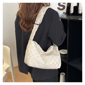 Sac bandoulière beige à carreaux minimaliste porté par un mannequin en costume