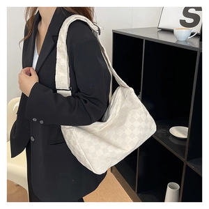 Detail of white nylon dumpling bag with woven checkered texture and adjustable shoulder strap