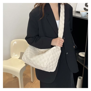 Detailed view of beige checkered hobo bag showing woven texture and wide shoulder strap