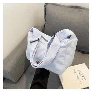 Detail of light blue woven hobo bag showing square textured pattern and adjustable strap