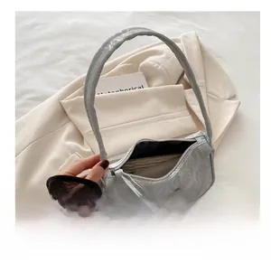 Silver pleated crescent bag with metallic bow detail showing interior storage capacity