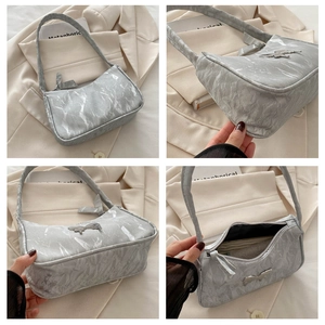 Detail view of silver pleated crescent bag featuring metal bow and interior capacity
