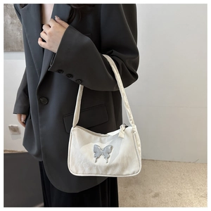 Chic white underarm bag with silver butterfly metal buckle worn with casual suit