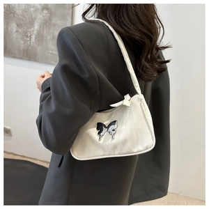 Detail showing white leather hobo bag with a metallic silver butterfly ornament