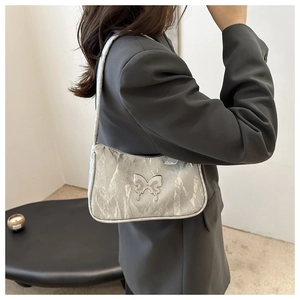 Close-up of metallic pleated silver shoulder bag with liquid metal butterfly detail