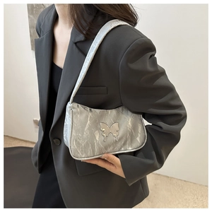Close-up of metallic silver pleated underarm bag with decorative butterfly metal buckle