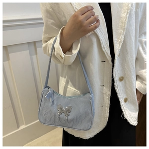 Close-up of light blue underarm bag with silver butterfly metal ornament and pleat texture