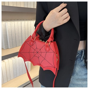 Red bat-shaped handbag with spider web stitching shown as a crossbody bag on a model