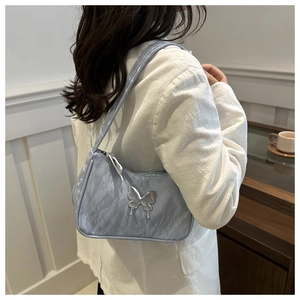 Detail of light blue pleated underarm bag with a silver liquid metal butterfly ornament