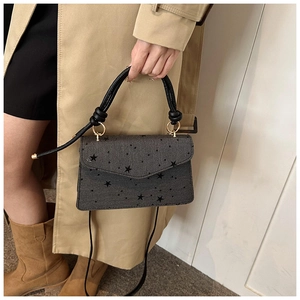 Detail der grauen Jeans-Handtasche mit schwarzen Sternen und runden Goldbeschlägen