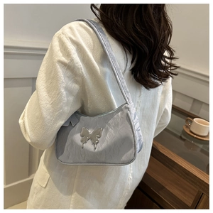 Detail of light blue pleated underarm bag with silver butterfly accessory on a model