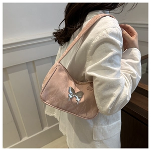 Close-up of pink butterfly shoulder bag with metallic decoration on a model