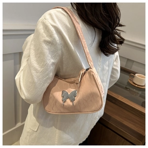 Detail of light pink ruched shoulder bag featuring a silver butterfly metallic ornament