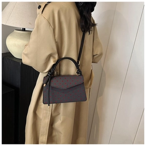 Schicke graue Umhängetasche mit Punkten, getragen zum klassischen Trenchcoat im eleganten Stil