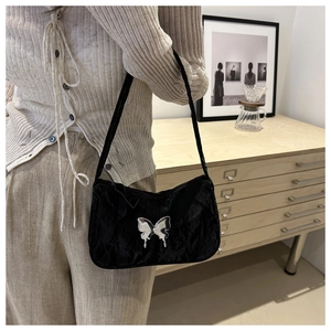 Detailed view of black pleated shoulder bag with a silver butterfly metal ornament