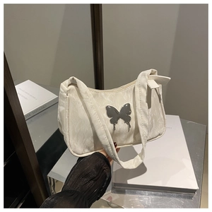 Detail of butterfly metal ornament and marble texture on beige shoulder bag