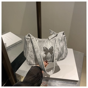 Detail of silver metallic pleated hobo bag with a decorative vintage metal butterfly