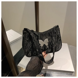 Detail of black pleated fabric texture with silver butterfly metal ornament on a chic bag