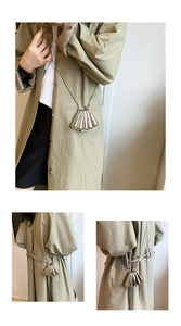 Detail showing shell-shaped silver metal mini crossbody bag worn with a chain strap