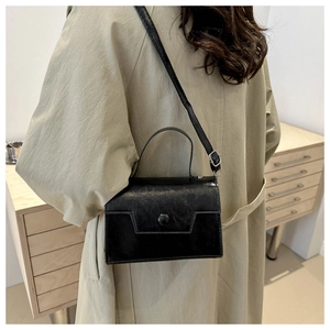 Détail d'un sac à main minimaliste en cuir poli noir avec rabat géométrique élégant
