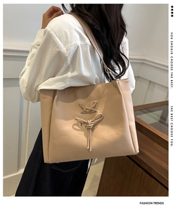 Detail view of beige bow-knot tote bag showing elegant side profile and shoulder strap