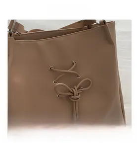 Detail of beige tote bag featuring crossover lace-up design and metal eyelets