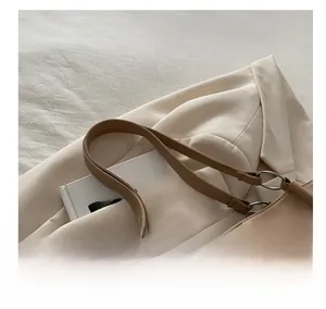 Detail of soft beige leather tote bag with unique twisted shoulder strap and metal rings