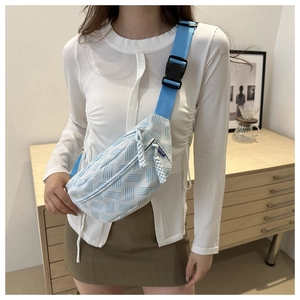 Detail of light blue textured waist bag showing fabric pattern and fashion label