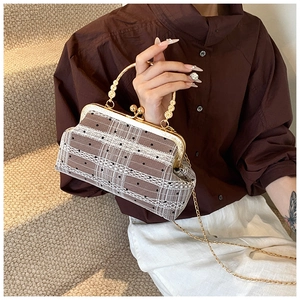 Detailed view of brown plaid shell bag with white polka dot lace and gold metal handle